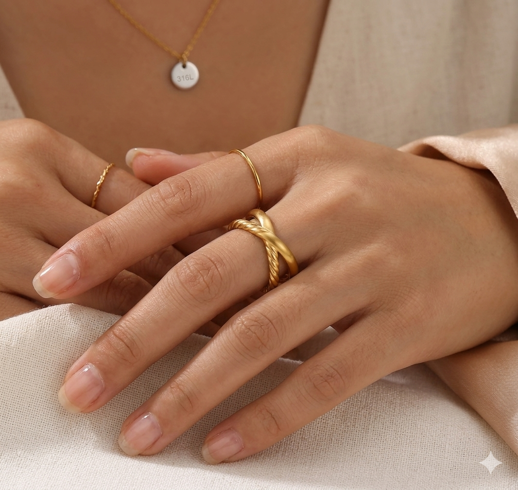Close-up of a hand wearing gold rings on a neutral background