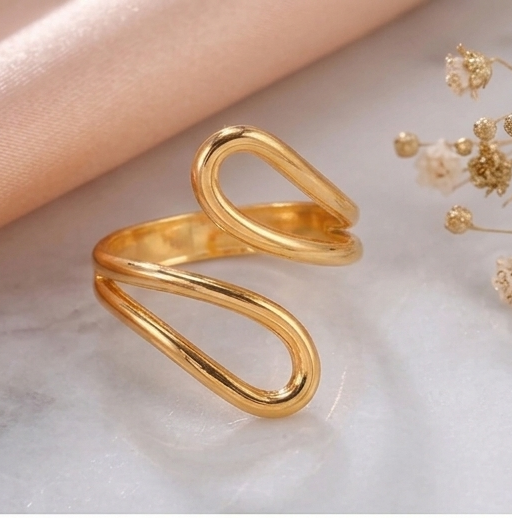 Gold ring on a marble surface with a cup of tea and flowers in the background