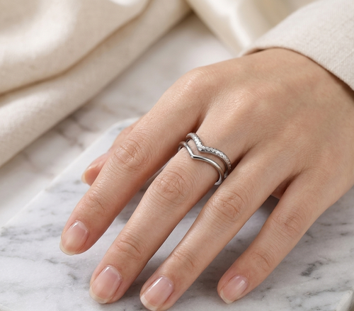 Hand wearing a silver ring on a marble surface