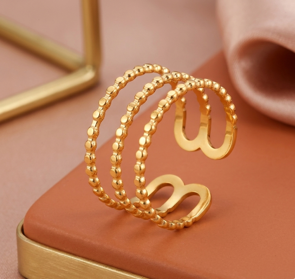 Gold bracelet on a pink surface with a soft focus background