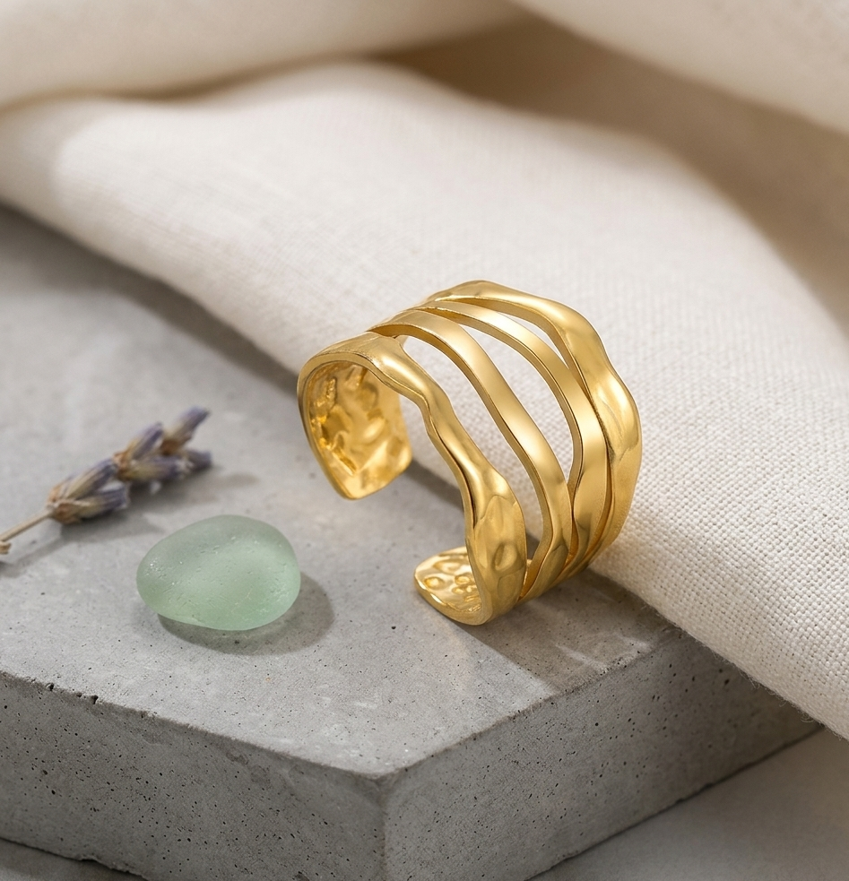 Gold bracelet on a textured surface with lavender and a green stone