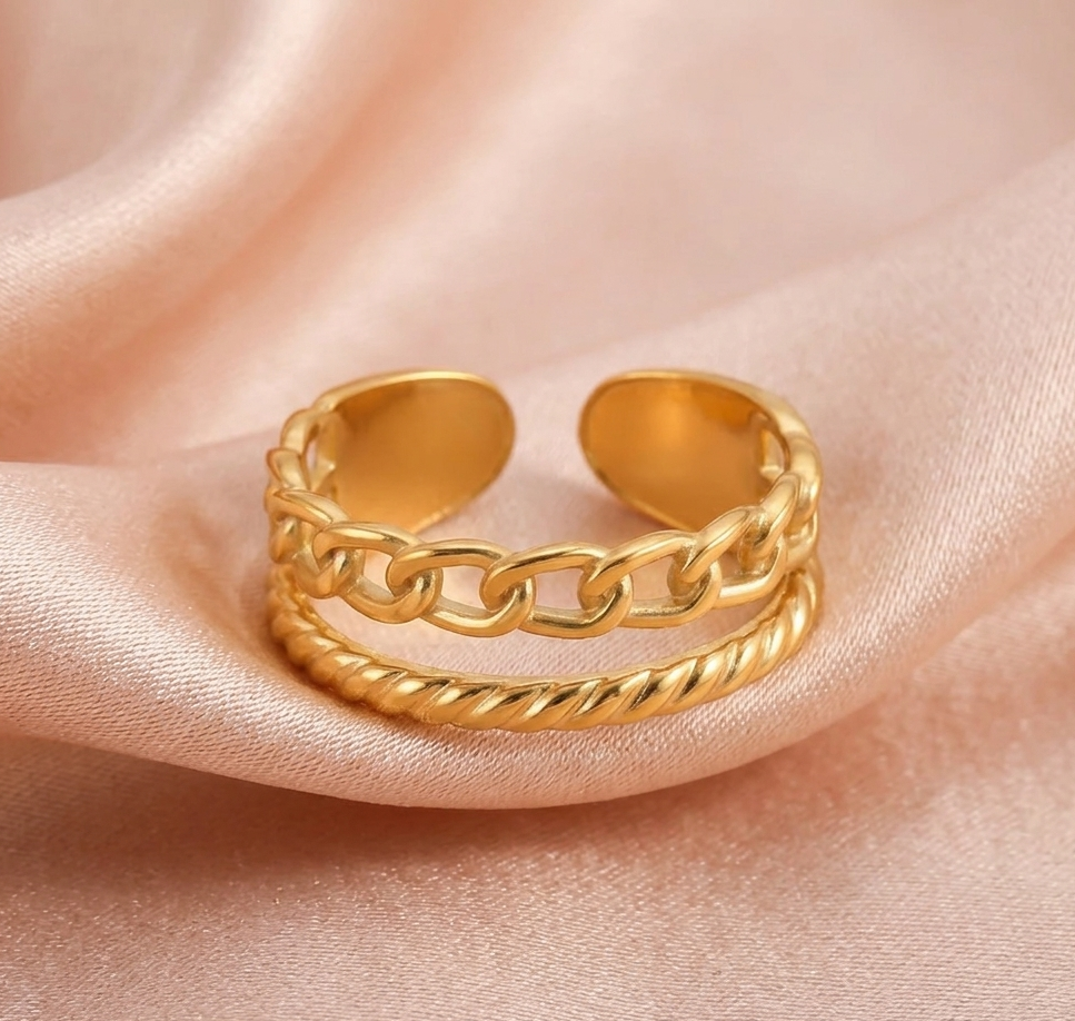 Gold chain ring on a soft pink fabric background