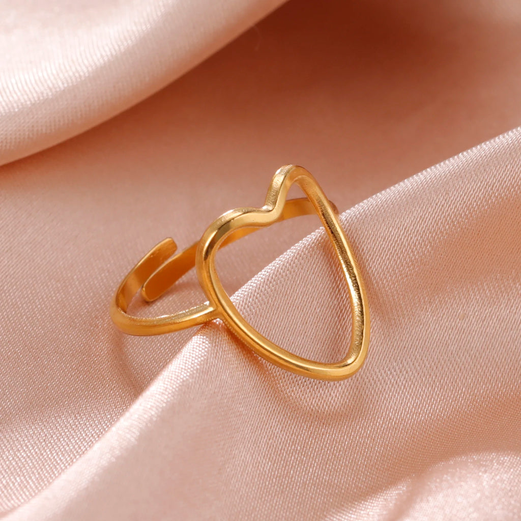 Gold heart-shaped ring on a soft pink fabric background