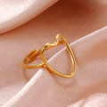 Gold heart-shaped ring on a soft pink fabric background