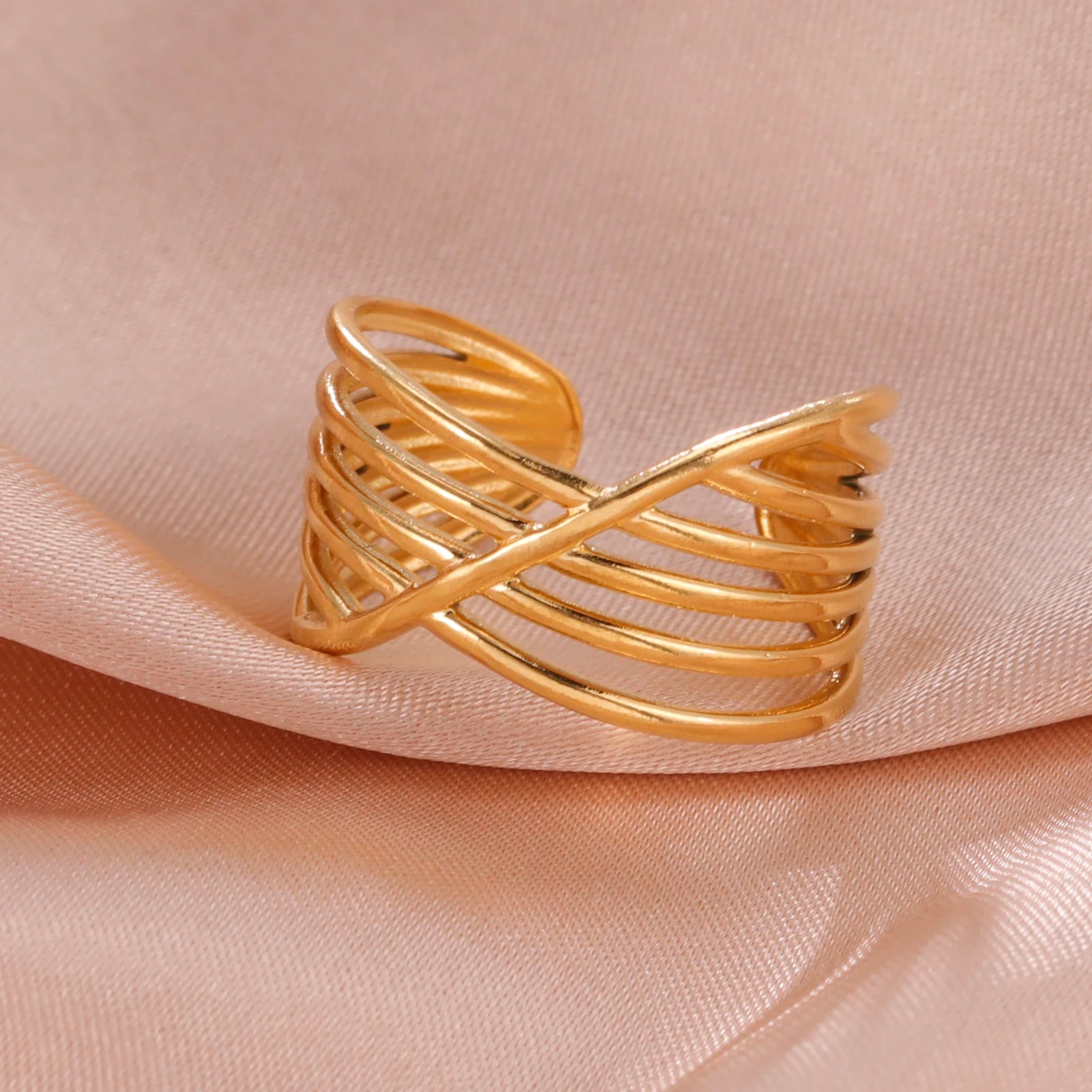 Gold open ring on a soft pink fabric background