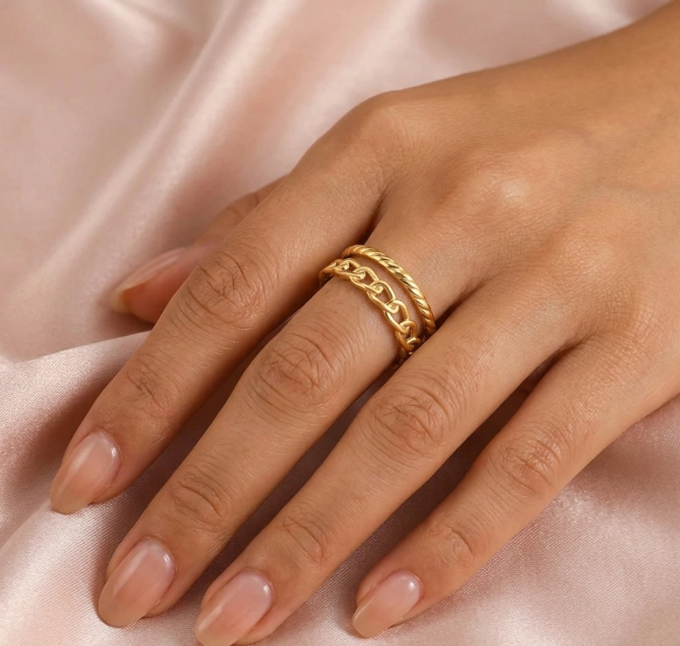 Gold ring on a hand with a soft pink fabric background