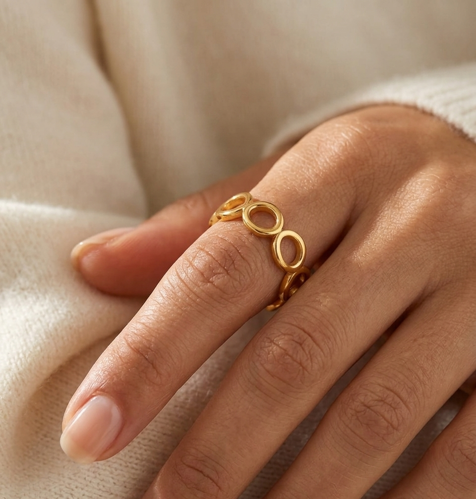 Gold ring on a person's finger against a neutral background