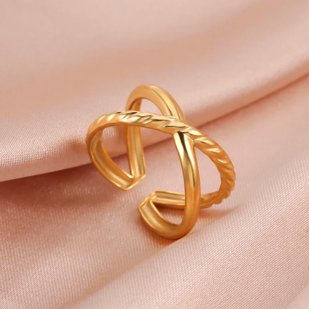 Gold ring with a twisted design on a soft pink fabric background