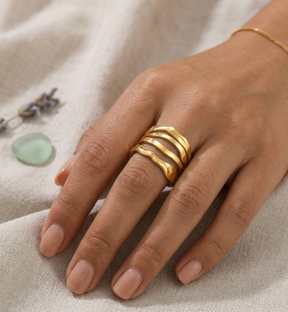 Hand wearing a gold ring on a textured beige fabric background
