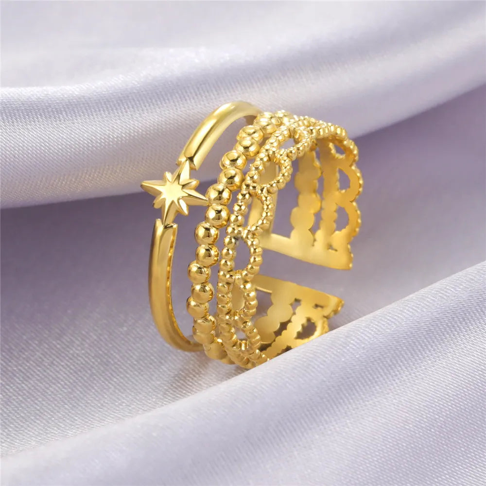 Set of gold rings with intricate designs on a white fabric background