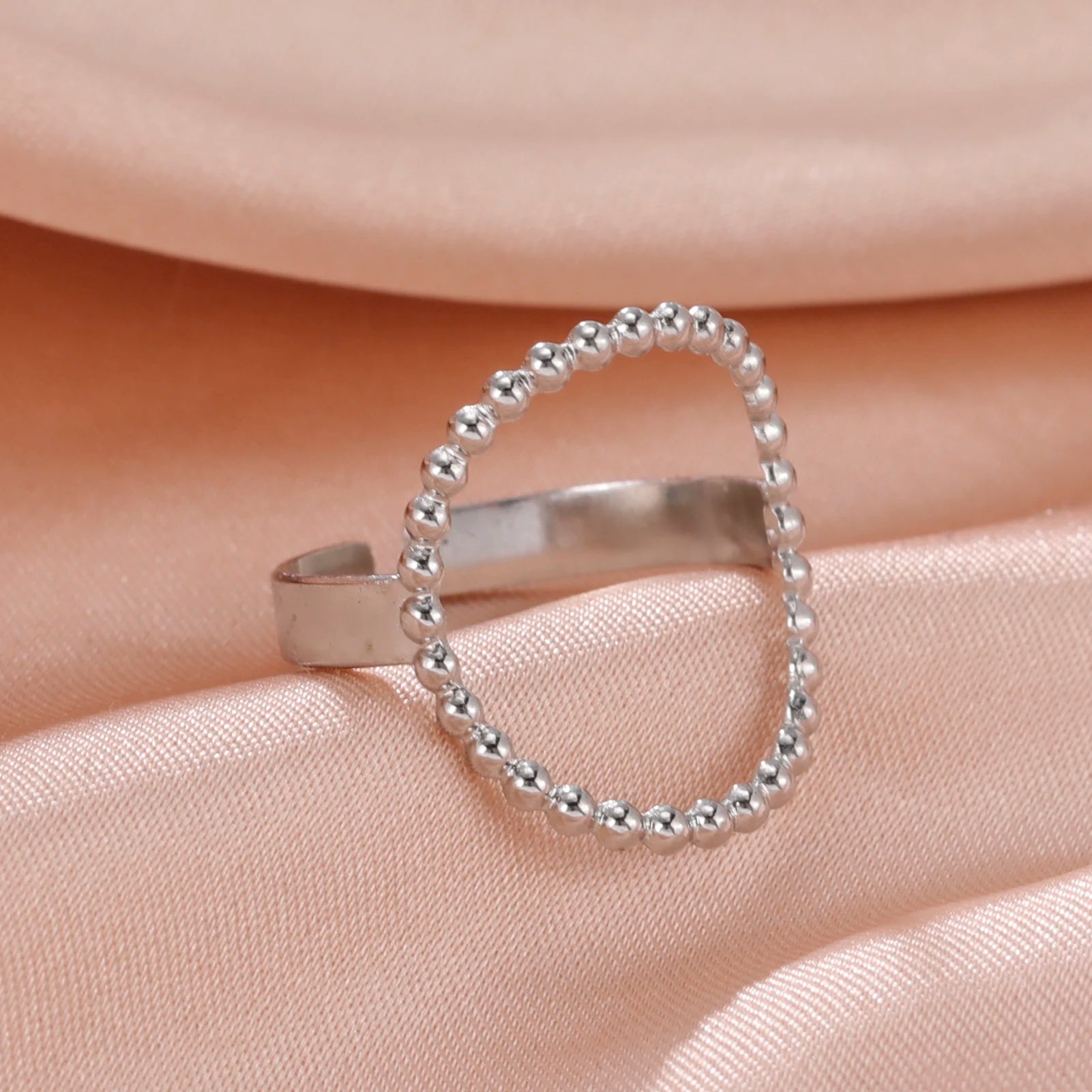 Silver beaded ring on a soft pink fabric background