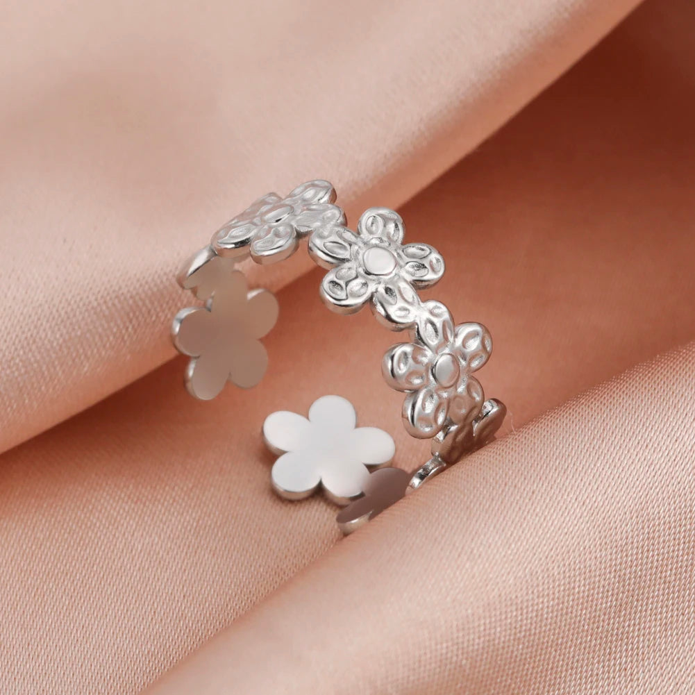 Silver flower-shaped ring on a soft pink fabric background