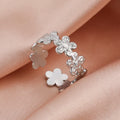 Silver flower-shaped ring on a soft pink fabric background