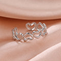 Silver heart-shaped ring on a soft pink fabric background