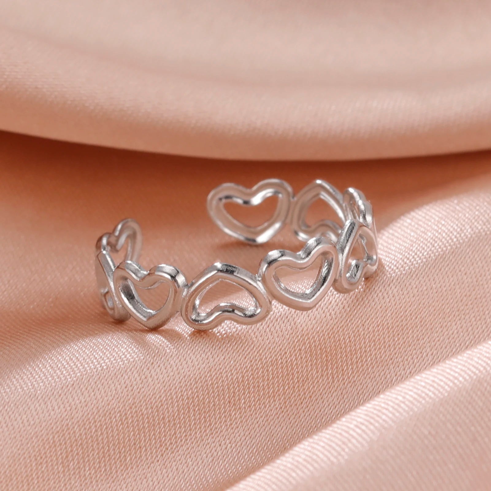 Silver heart-shaped ring on a soft pink fabric background