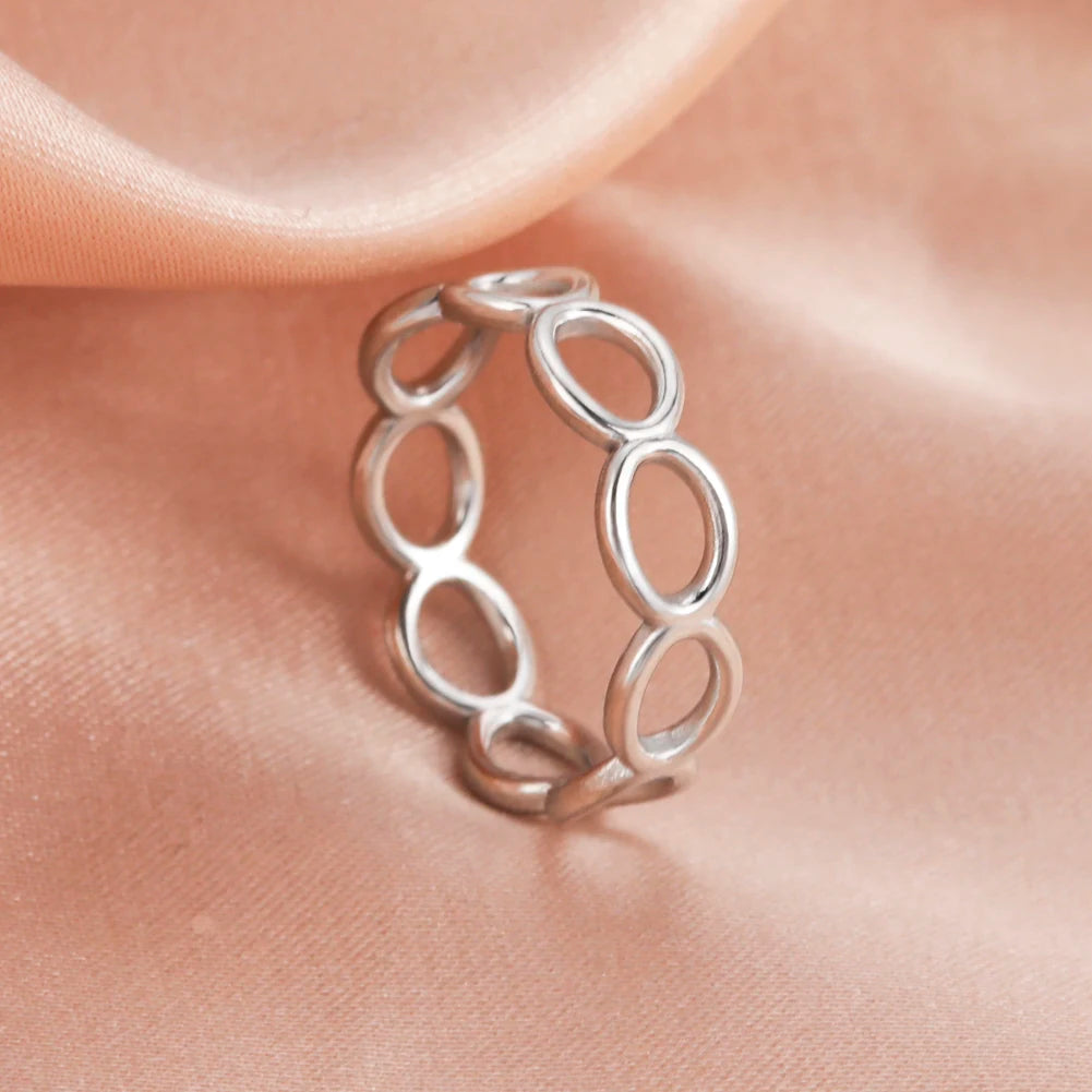 Silver ring with interlocking loops on a soft pink fabric background